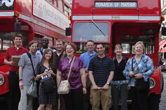 A group stands in front of buses at the Covent Garden in London.
